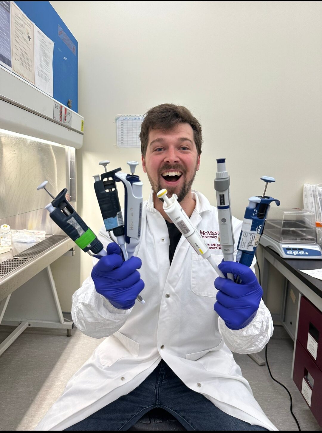 Person in lab cost with pipettes in hands