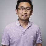 Man in purple shirt in front of grey background