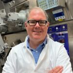 Man in lab coat in front of scientific equipment