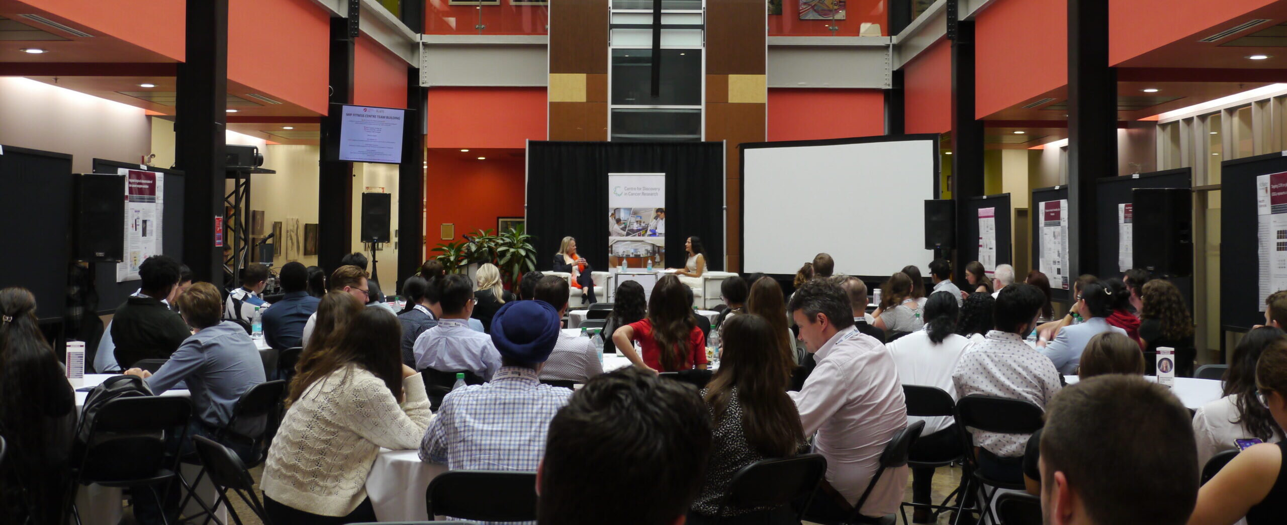 Crowd watching two people speak in white chairs on a stage