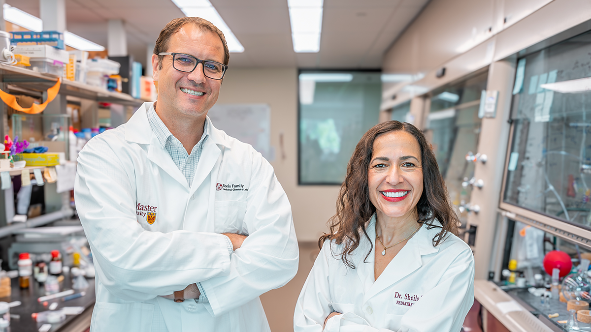 Two scientists in lab coats smiling and in a lab.